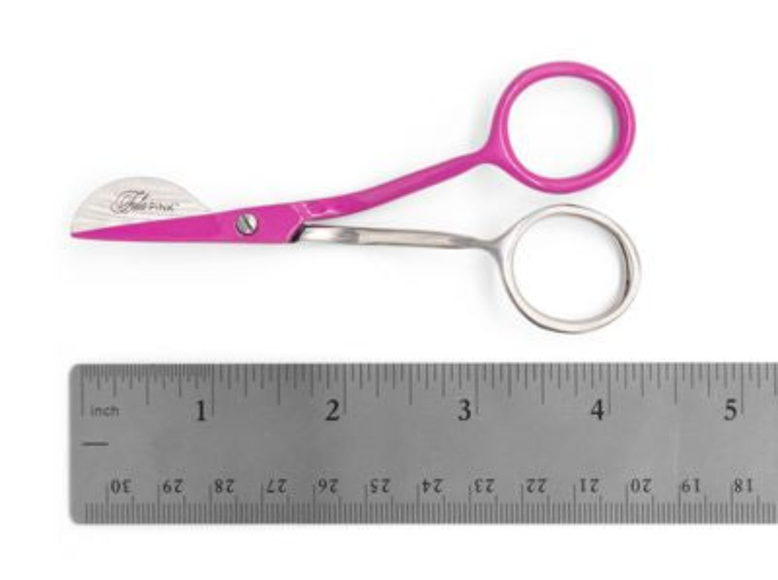 Pink and silver scissors with a circular ring handle, shown above a metal ruler on a white background. The brand name 'Tula PINK' is engraved on the blade.