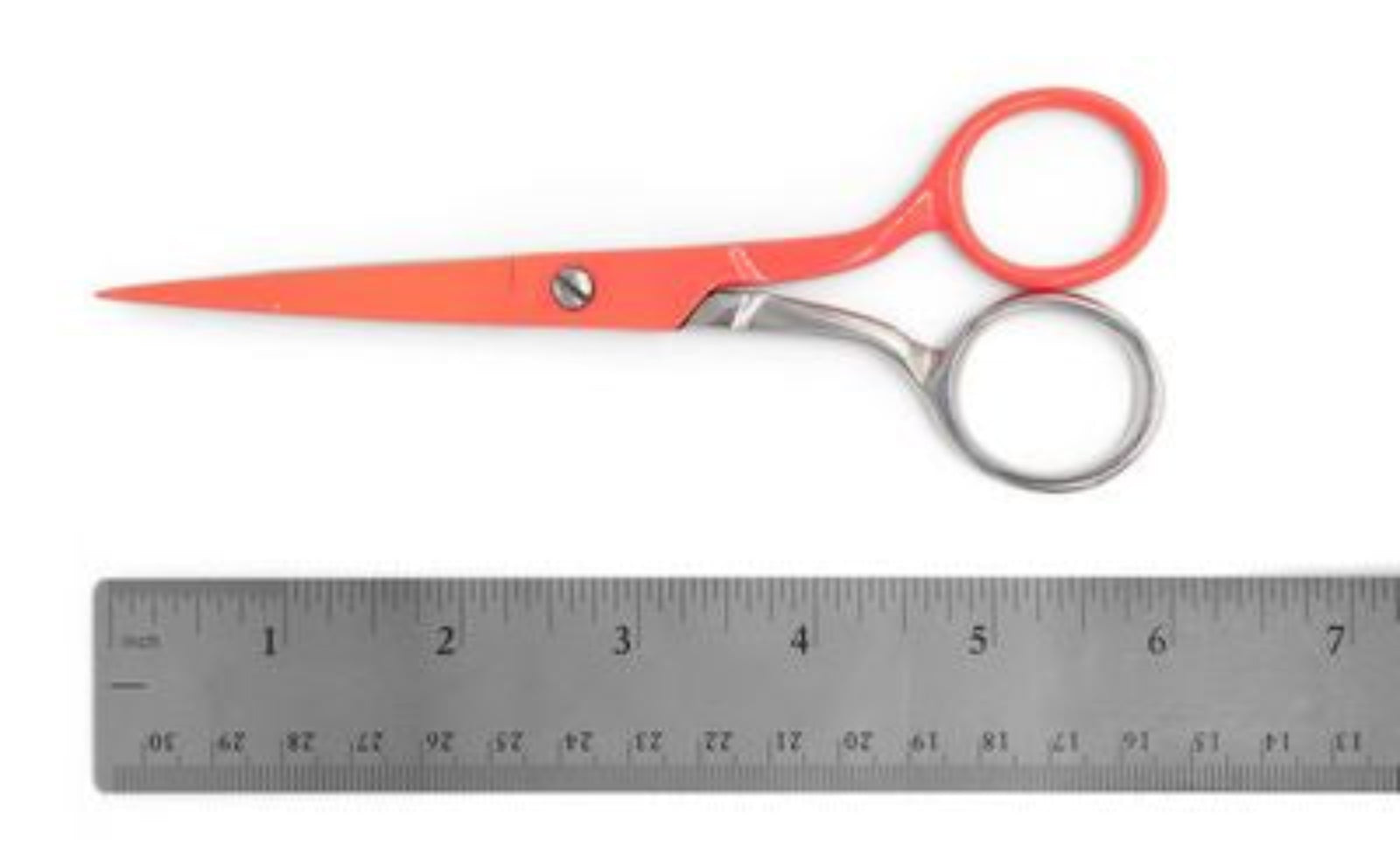 Red-handled scissors with silver metal blades and handles, shown above a metal ruler on a white background.