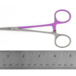 Small silver hemostat with purple handles placed above a metal ruler on a white background.