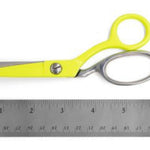 Bright yellow-handled scissors with silver metal blades and a metal loop, shown above a gray ruler on a white background.