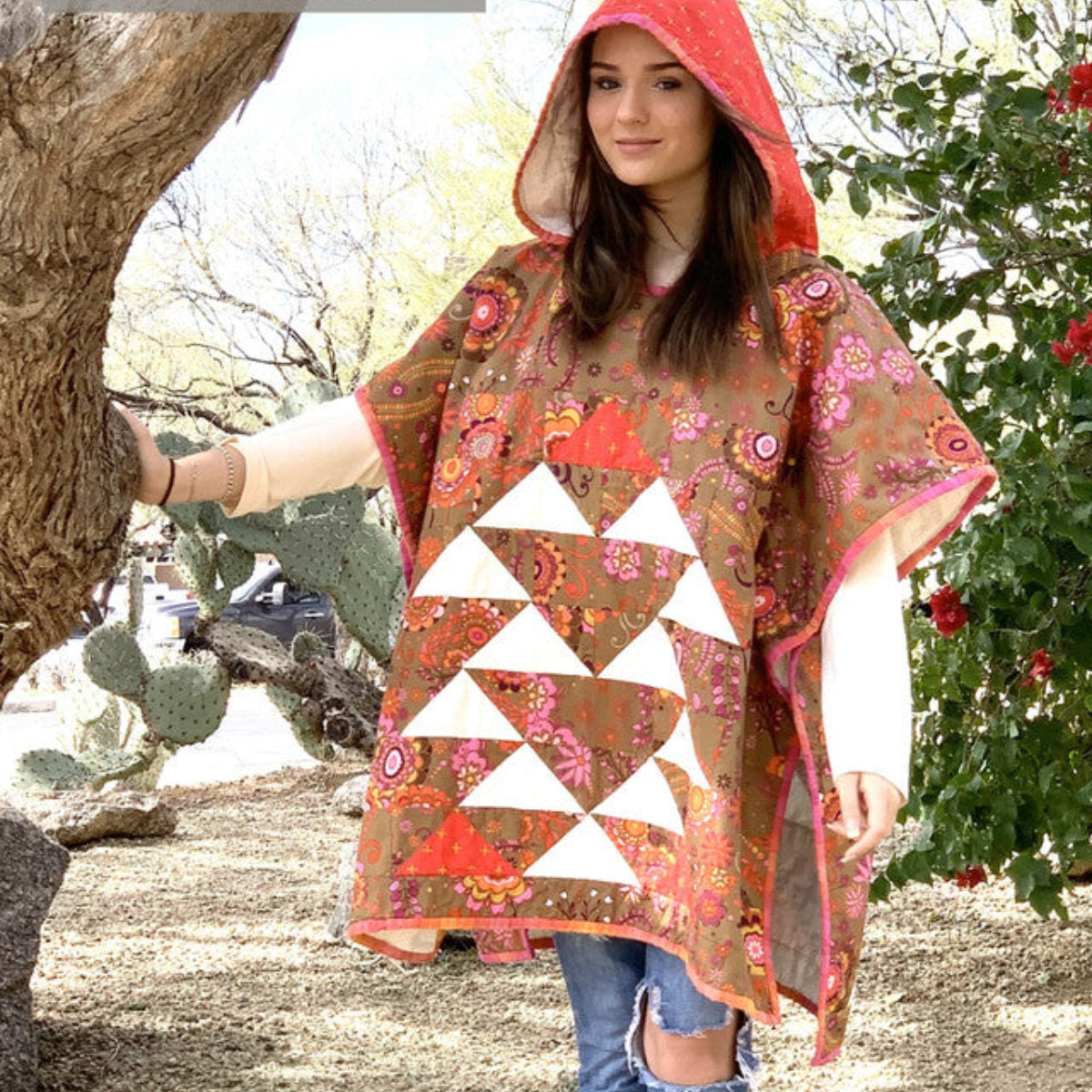 Woman wearing a floral poncho with a hood in a natural setting, promoting Cotton Street Commons.