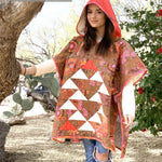 Woman wearing a floral poncho with a hood in a natural setting, promoting Cotton Street Commons.