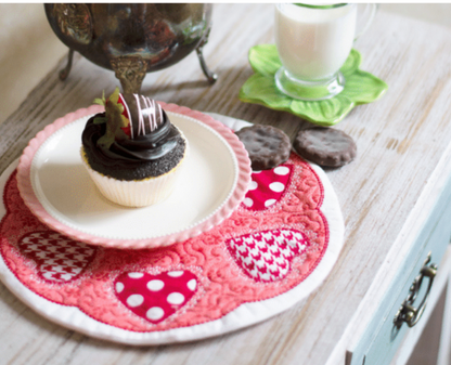 Cupcake on a decorative plate with heart patterns on a wooden table.
