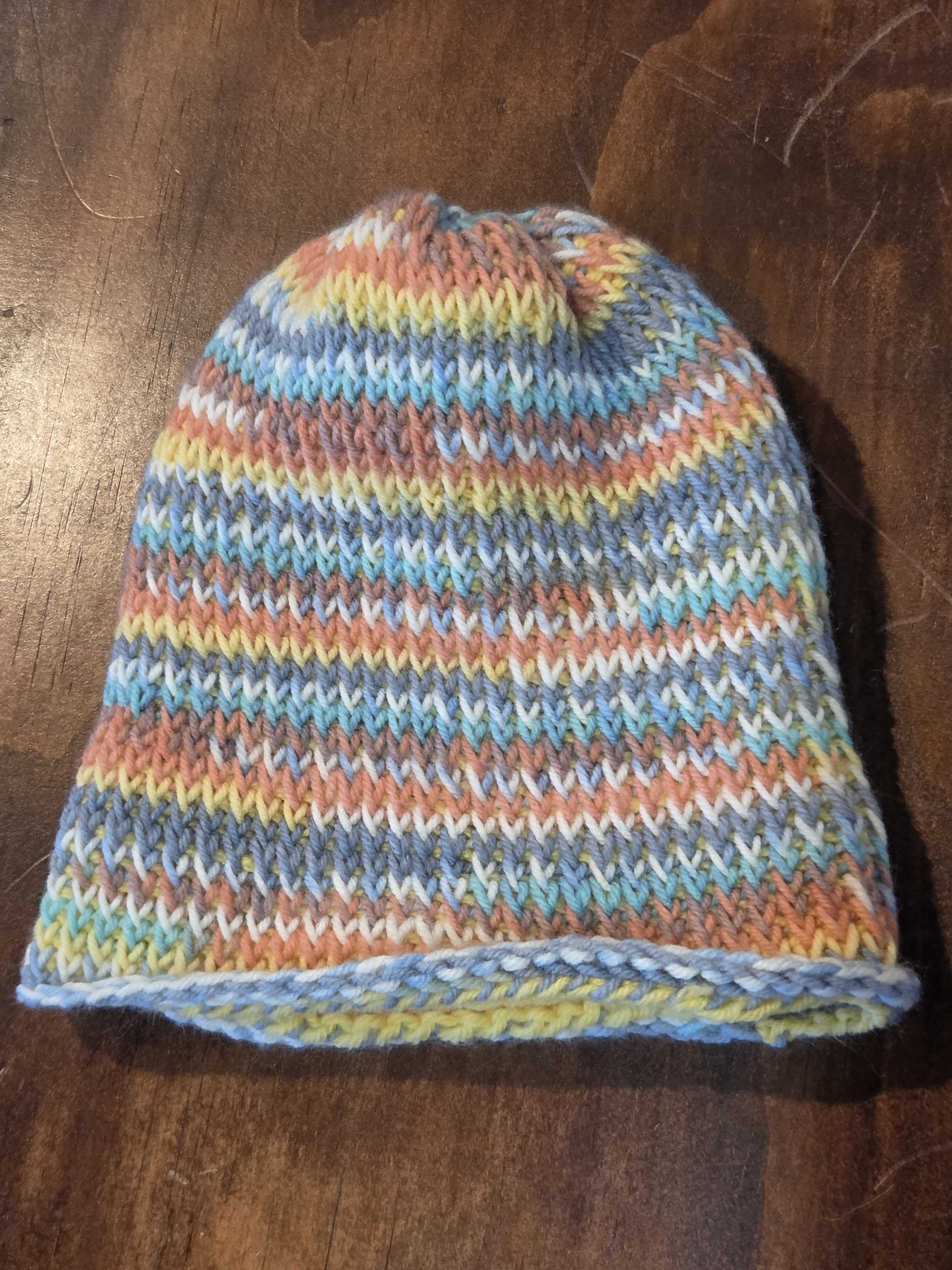 Tunisian crochet hat with the brim unfolded, showing colorful pastel stripes and clear stitch texture.