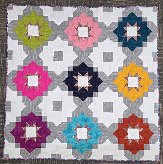 Vintage Tiles quilt featuring colorful geometric star blocks in a modern repeating layout.