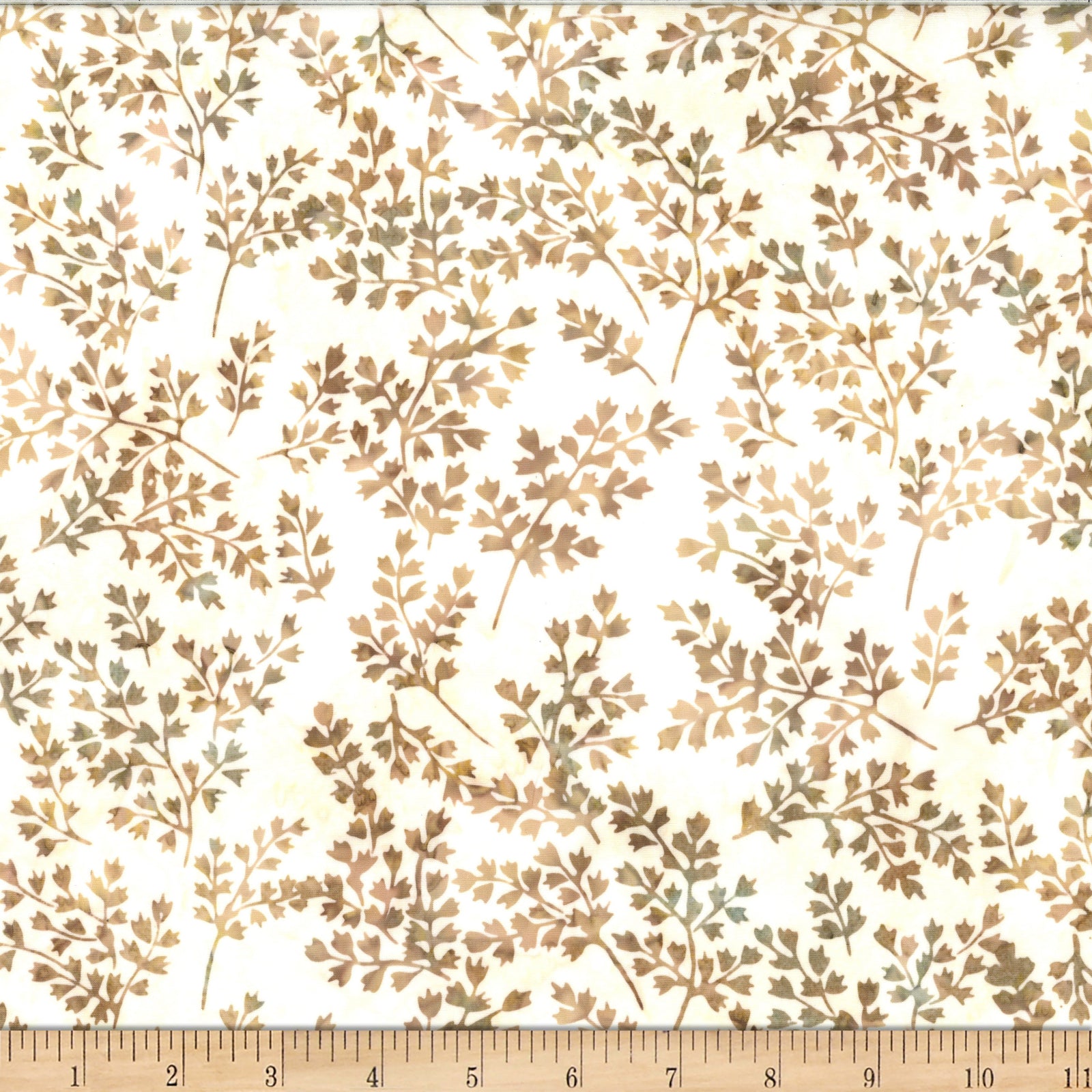 A close-up of a fabric or wallpaper pattern featuring delicate brown and muted olive-green leafy branches on a warm cream background, with a wooden ruler at the bottom showing scale.