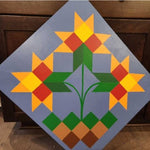Painted barn quilt featuring three geometric floral motifs in yellow, orange, red, and green on a blue background.