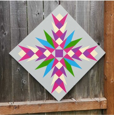 Painted barn quilt featuring a colorful geometric starburst design in pink, purple, green, and blue.