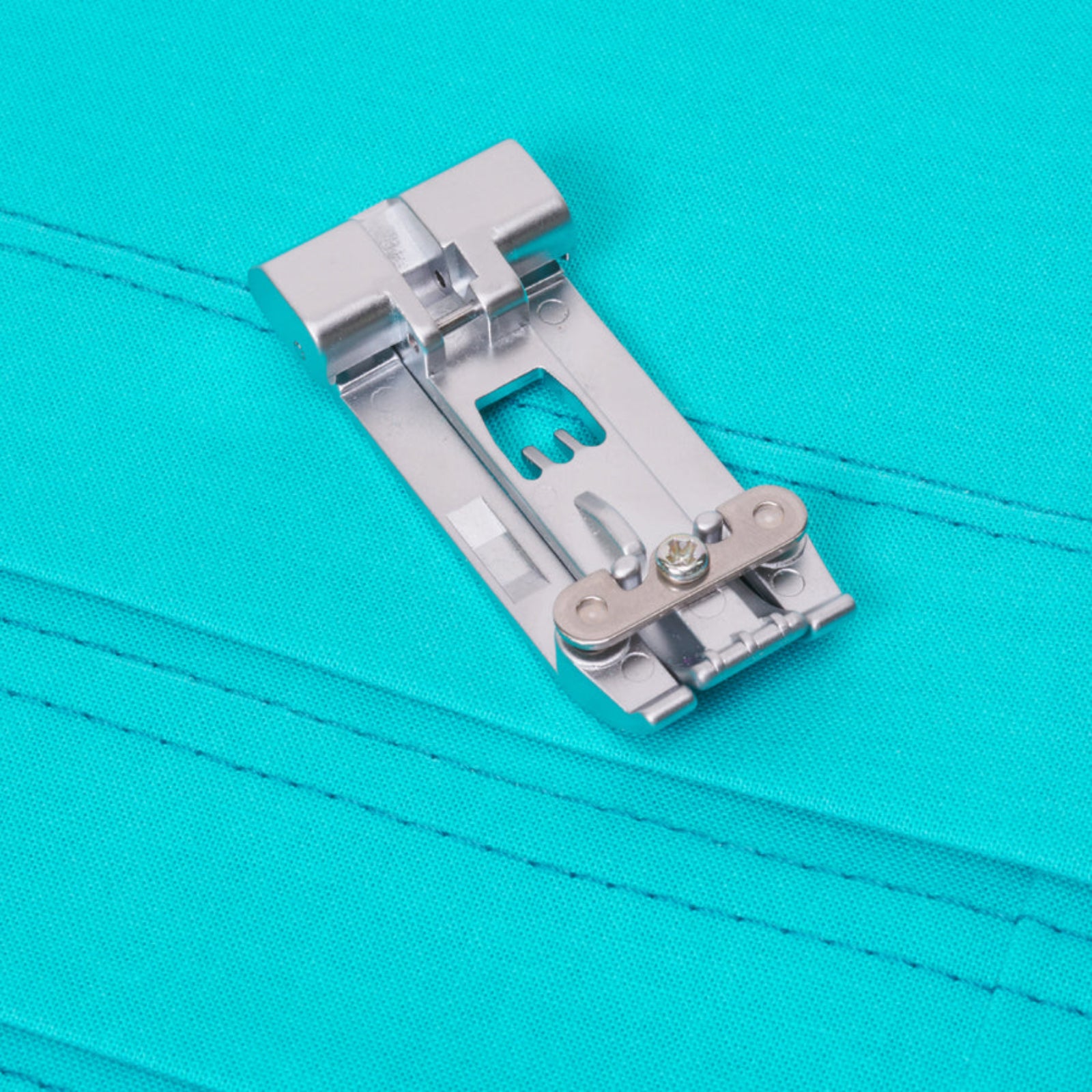 Metal sewing machine presser foot on a turquoise background