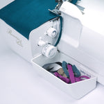 Sewing machine with a bobbin case containing colorful thread on a white background