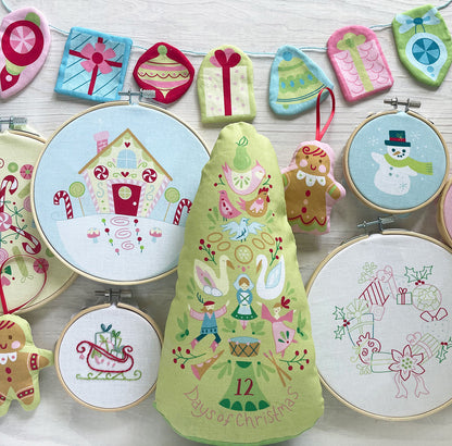 Embroidery hoops with festive designs including gingerbread men, a snowman, and Christmas trees on a white background.