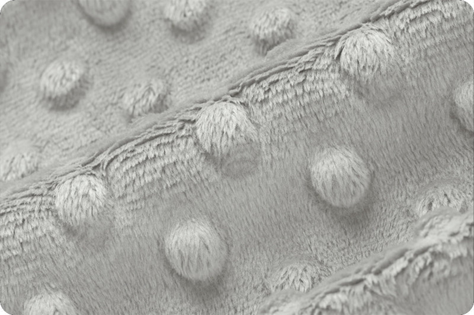 Close-up of a light gray textured fabric with raised circular tufted dots and a soft fuzzy border.