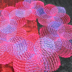 Close‑up of an embroidered design created with automatic color‑blending software techniques in pink and red tones.