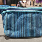 Blue striped Cuddle fabric zippered pouch displayed on a table with the background softly out of focus.