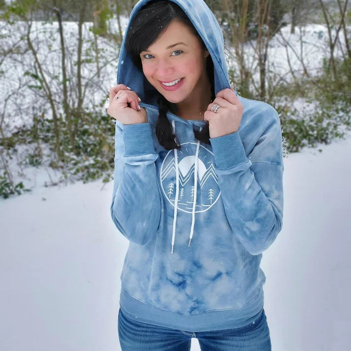 Outdoor winter view of the Del Mar Hoodie worn in the snow, showing the front design and hooded style