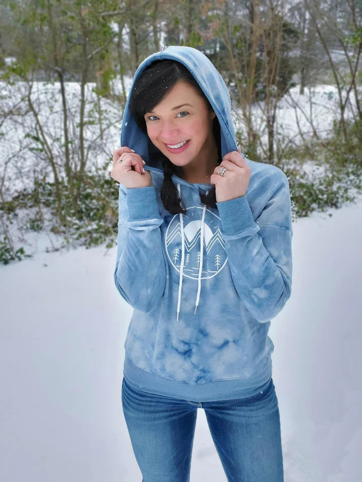 Outdoor winter view of the Del Mar Hoodie worn in the snow, showing the front design and hooded style