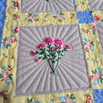 Close-up of embroidered floral quilt blocks with detailed quilting and colorful borders