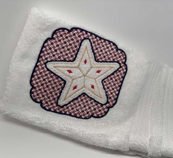 White hand towel with a stitched star design framed by a decorative embroidered border.