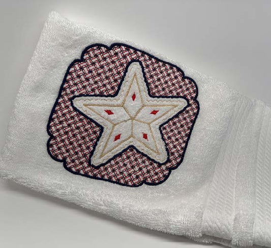 White hand towel with a stitched star design framed by a decorative embroidered border.
