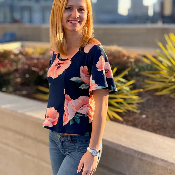 Outdoor urban view of the Florence Top worn with jeans, showing the clean neckline and floral knit fabric in natural light