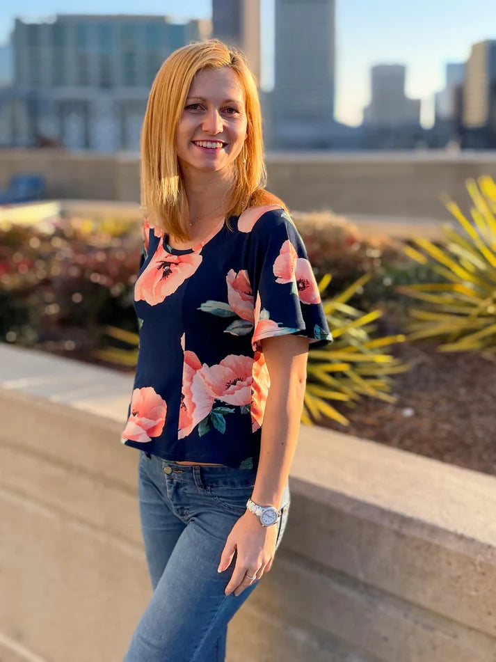 Outdoor urban view of the Florence Top worn with jeans, showing the clean neckline and floral knit fabric in natural light