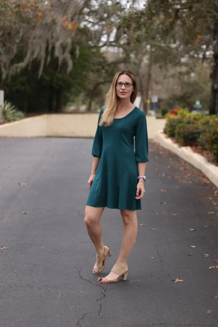 Outdoor view of the Florence Tunic worn in a knee‑length option with three‑quarter sleeves, shown in a natural garden setting