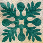 Teal appliqué block with symmetrical leaf shapes on a cream quilted background, used as a hand‑quilting sample.
