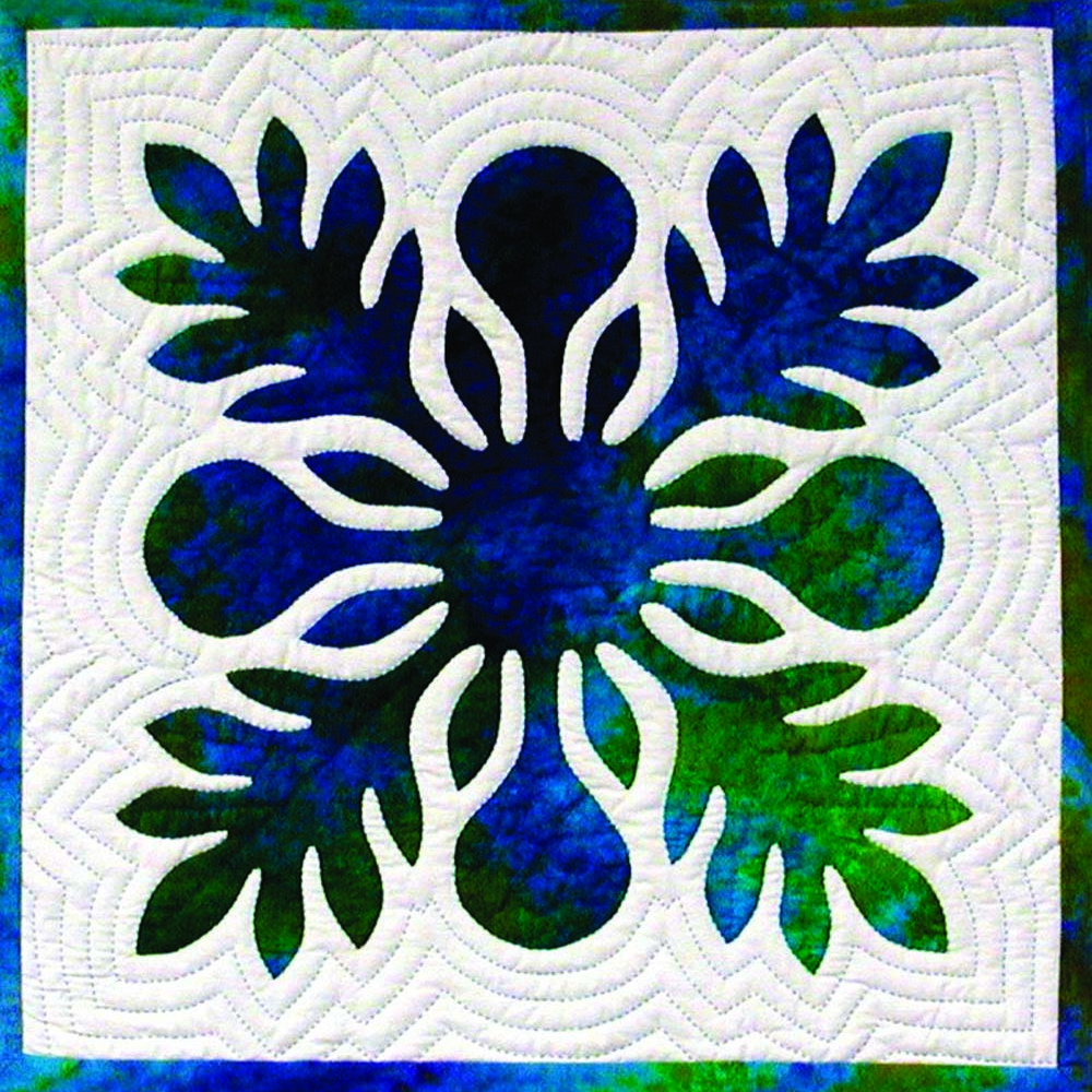 Hand‑appliquéd Hawaiian quilt block with layered blue and green fabric and echo quilting.