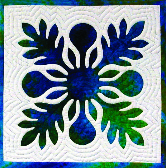 Hand‑appliquéd Hawaiian quilt block with layered blue and green fabric and echo quilting.