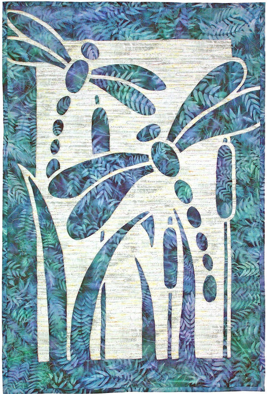 Nature‑themed appliqué design with two dragonflies and cattails cut from blue and green fabric against a textured background