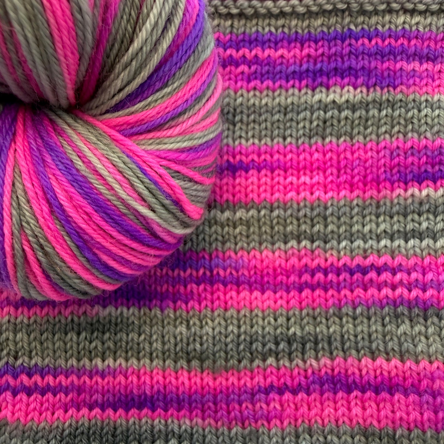 Knitted swatch showing how Cozy Craft Coven’s self‑striping yarn works up in color.