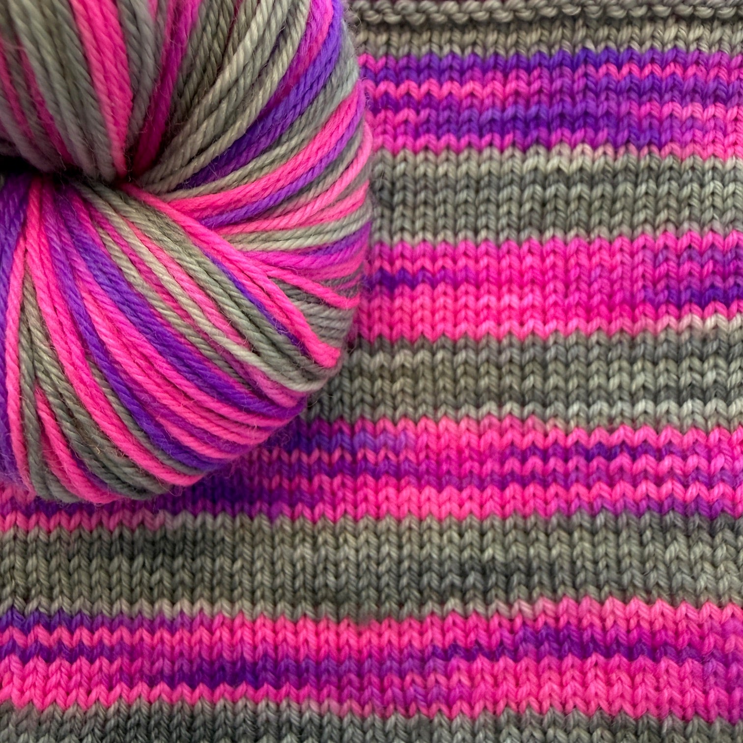 Knitted swatch showing how Cozy Craft Coven’s self‑striping yarn works up in color.