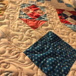 Close-up of a quilt block with blue and red fabrics and detailed swirling quilting