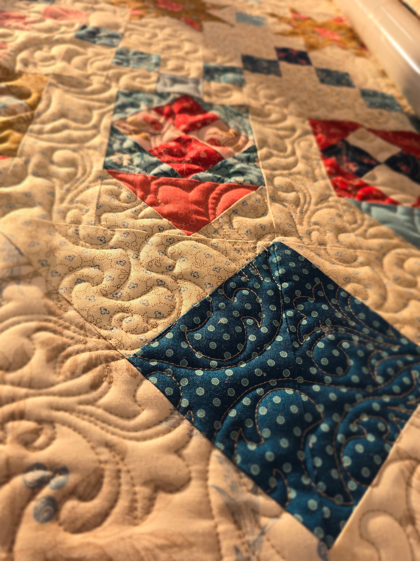 Close-up of a quilt block with blue and red fabrics and detailed swirling quilting