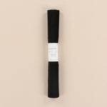 Roll of black velvet with a label on a beige background