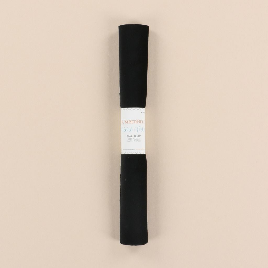 Roll of black velvet with a label on a beige background