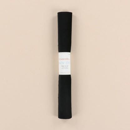 Roll of black velvet with a label on a beige background