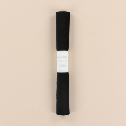 Roll of black velvet with a label on a beige background