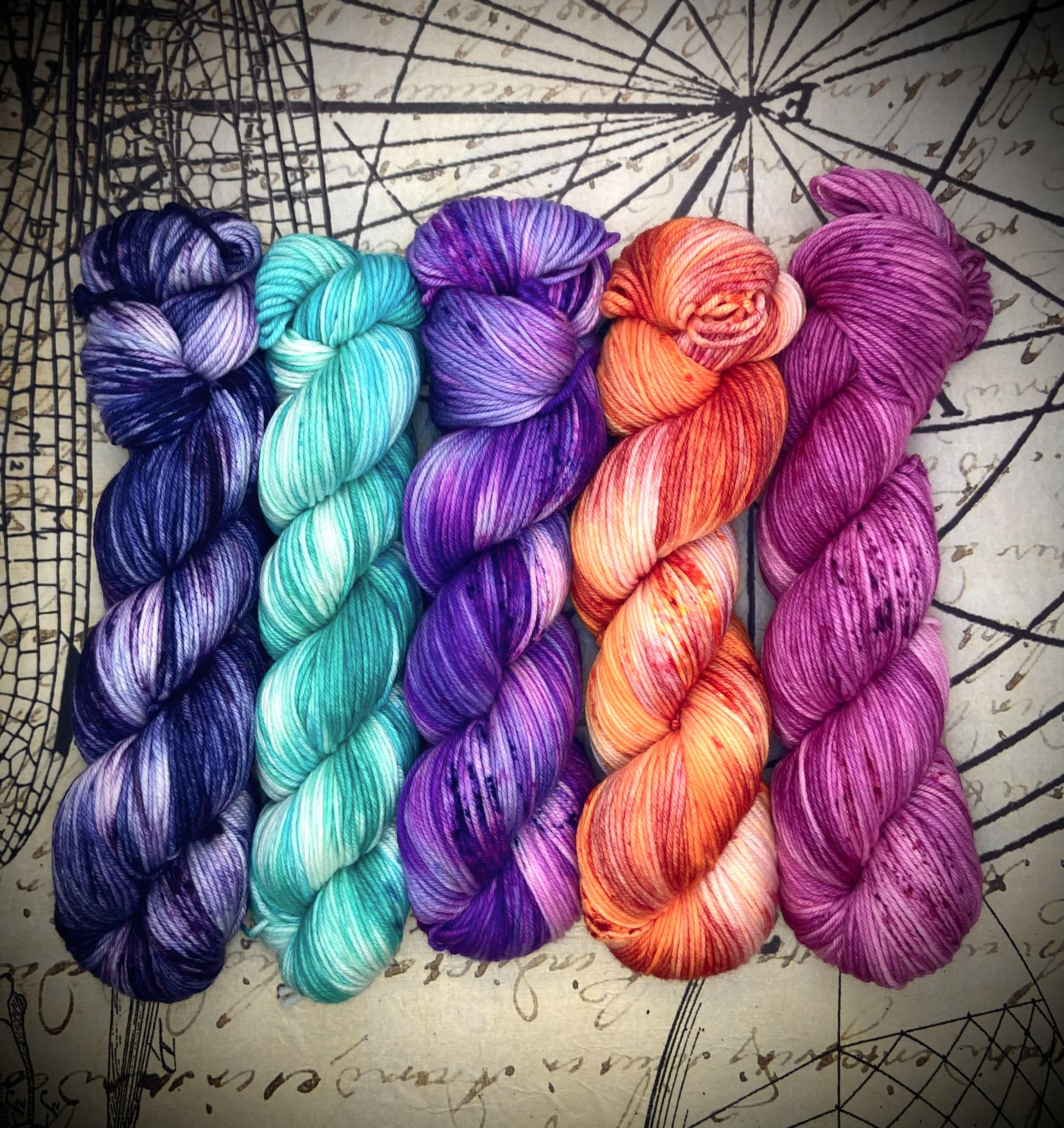 Five hand‑dyed yarn skeins in a fade set featuring blue, turquoise, purple, orange, and magenta tones.