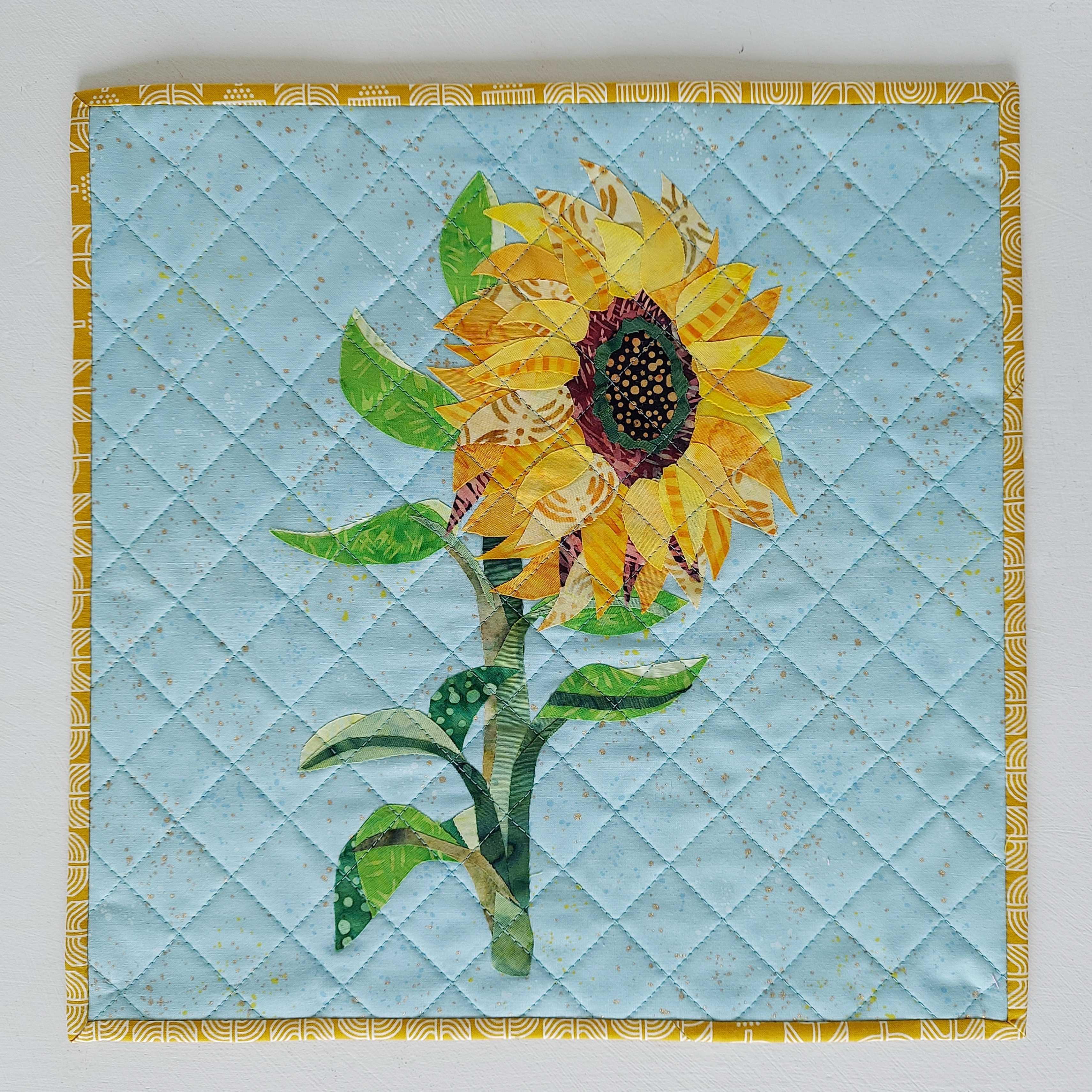 Sunflower collage created with layered fabric pieces using the parchment pressing technique, taught by instructor Kim Andersen.