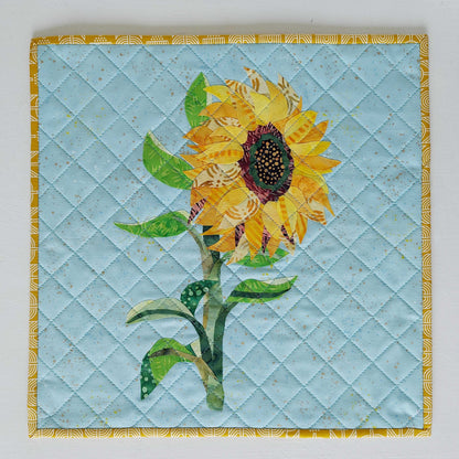 Sunflower collage created with layered fabric pieces using the parchment pressing technique, taught by instructor Kim Andersen.