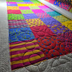 Longarm quilting machine stitching curved patterns across a colorful patchwork quilt