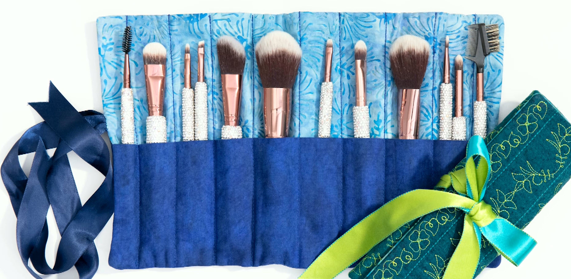 Makeup brush roll with turquoise interior and embroidered floral exterior, shown open and closed.