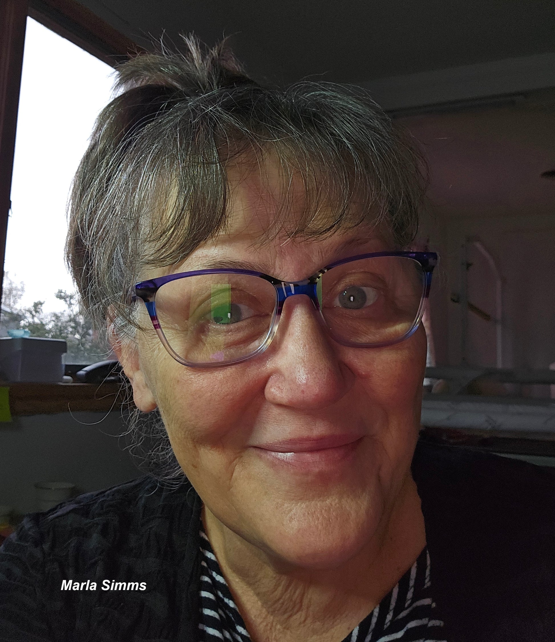 Portrait of Handi Quilter educator Marla Simms wearing glasses and smiling indoors