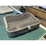 Finished Pack It In 2.0 bag sewn by Sonia, shown on a cutting mat with the mesh top and double zipper visible.