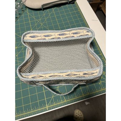 Finished Pack It In 2.0 mesh bag sewn by Sonia, shown on a cutting mat with the mesh panel and fabric edging visible.