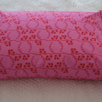 Handmade pink pillowcase with a red floral print, displayed on a white quilted bed.