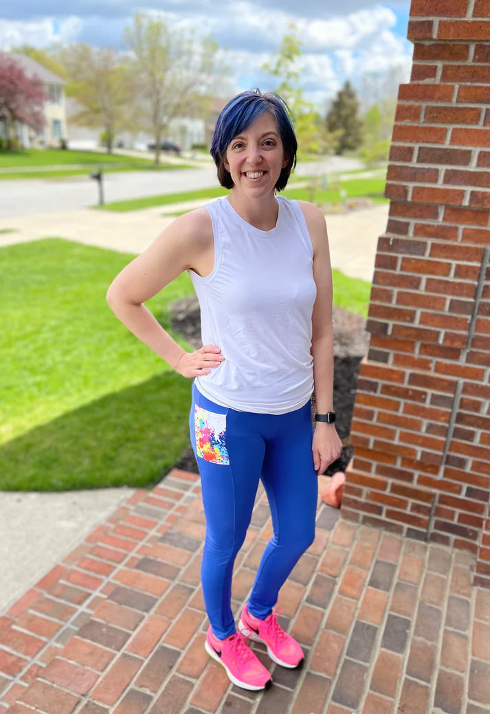 Outdoor view of the Pittsburgh Walking Pants sewn as leggings with a patterned pocket panel, worn with a sleeveless athletic top on a brick porch