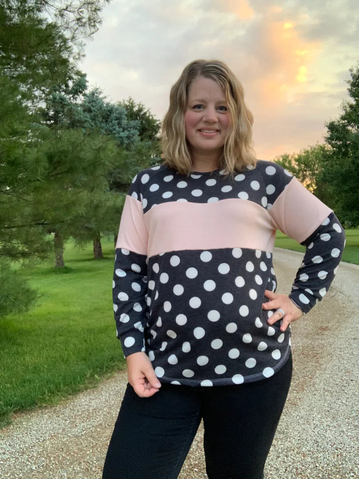 Outdoor view of the Santa Fe Top sewn without a hood, featuring long sleeves and a polka‑dot and color‑block design, worn at sunset on a gravel path