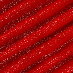 A close-up of red fabric with a diagonal striped pattern created by folds, covered in small white speckles.